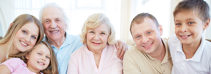 Portrait Of Senior And Young Couples With Their Children Looking At Camera At Home